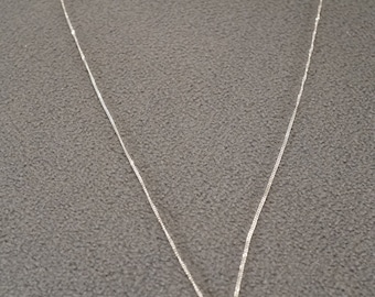 May include: A silver chain necklace with a small pink gemstone pendant.