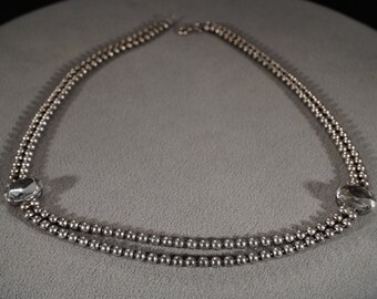 May include: A silver necklace with two strands of small beads and two large, clear crystal accents.