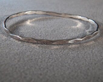 May include: A silver bangle bracelet with a hammered texture.
