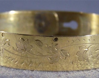 May include: A gold-toned bangle bracelet with a floral design. The bracelet has a hinged clasp.