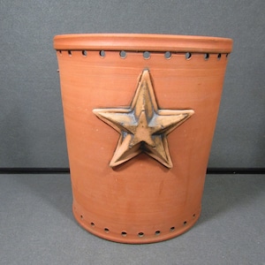 May include: Terracotta planter with a star design. The planter has a brown glaze and is decorated with a five-pointed star in a lighter shade of brown.