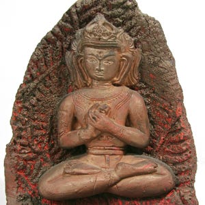 May include: A seated Buddha statue with hands clasped in prayer. The figure is a reddish-brown color and is set against a textured, dark red and brown background. The statue is a representation of peace and meditation.