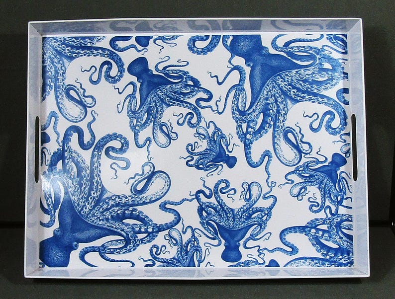 May include: Rectangular serving tray with a white background and a repeating pattern of blue octopuses. The tray has a white border with integrated handles, offering a nautical or coastal theme. The octopus illustrations are detailed and artistic.