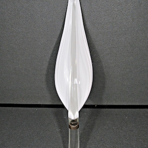 May include: A clear glass object with a white, petal-like shape. The object has a clear, cylindrical base with a metal band. The white portion has a textured, swirled design. The object is likely a decorative piece.