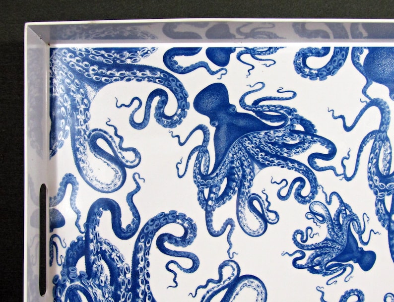 May include: A white serving tray with a repeating pattern of blue octopuses. The octopuses are depicted in a detailed, vintage style, with their tentacles curling across the tray's surface. The tray has a white border and cut-out handles.