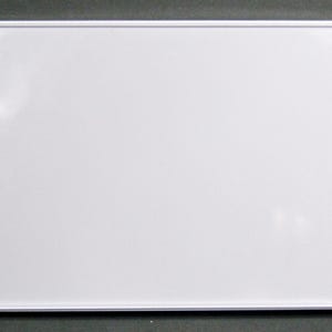 May include: A rectangular white dry-erase board with a white frame. The board is clean and blank, ready for use. The frame has a thin profile and is made of a glossy white material. The board is set against a dark gray background.