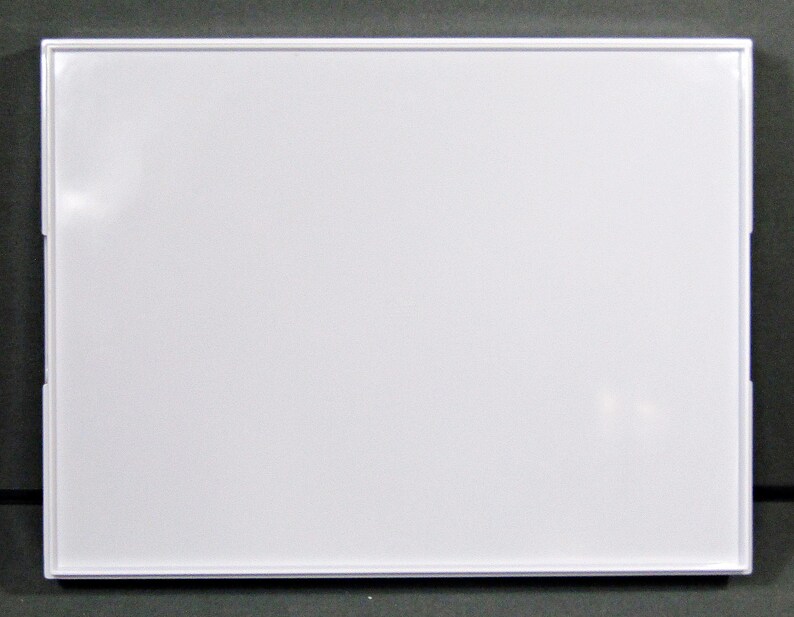 May include: A rectangular white dry-erase board with a white frame. The board is clean and blank, ready for use. The frame has a thin profile and is made of a glossy white material. The board is set against a dark gray background.