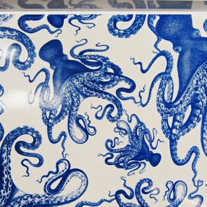 May include: White surface with a repeating pattern of blue octopuses. The octopuses are detailed with tentacles and suction cups, creating a nautical or marine theme. The design is reminiscent of a vintage illustration.