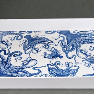 May include: A white rectangular serving tray with a blue octopus pattern on the interior. The octopus design is repeated across the white surface. The tray has a simple, clean design with integrated handles.