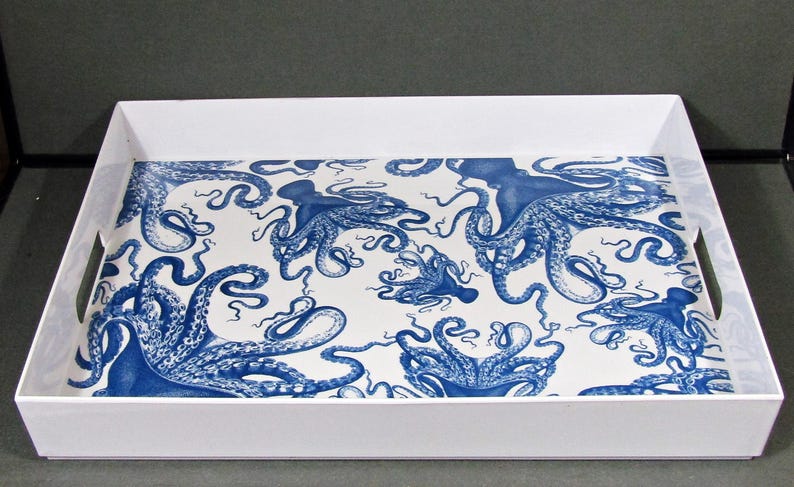 May include: A white rectangular serving tray with a blue octopus pattern on the interior. The octopus design is repeated across the white surface. The tray has a simple, clean design with integrated handles.
