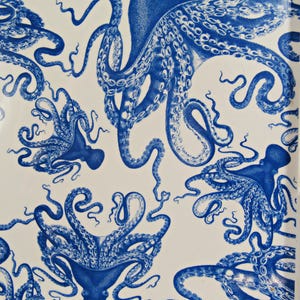 May include: A white serving tray with a repeating pattern of blue octopus illustrations. The octopus designs vary in size and orientation, creating a dynamic and visually engaging surface. The tray has a handle on the side.