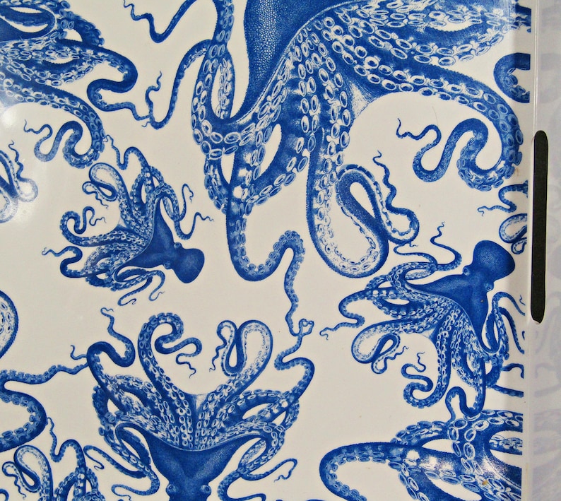 May include: A white serving tray with a repeating pattern of blue octopus illustrations. The octopus designs vary in size and orientation, creating a dynamic and visually engaging surface. The tray has a handle on the side.
