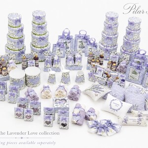 May include: A collection of miniature decorative items featuring lavender floral patterns and purple gingham accents, including stacked round boxes, gift bags, small pillows, towels, and containers, with the text Pilar Al&eacute;n and Lavender Love.
