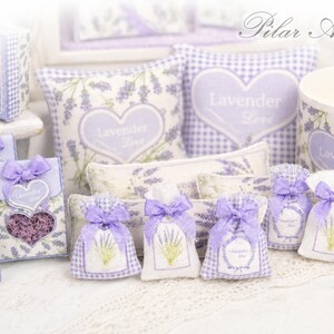 May include: A collection of lavender-themed items including small fabric sachets with purple bows, square pillows with heart motifs, and boxes featuring the text Lavender Love. The items display lavender sprig patterns and gingham accents.