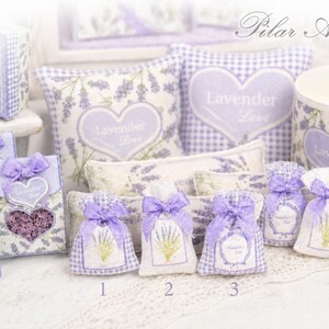 May include: A collection of lavender-themed items including small fabric sachets with purple bows, heart-shaped cutouts, and square pillows featuring lavender sprigs and the text Lavender Love. A cylindrical container and box are also present.