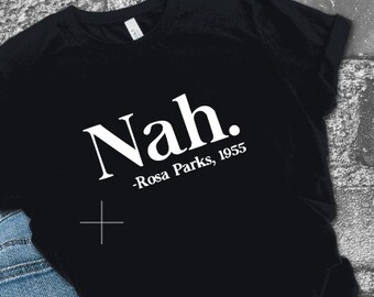 May include: Black t-shirt with white text that reads "Nah. -Rosa Parks, 1955"
