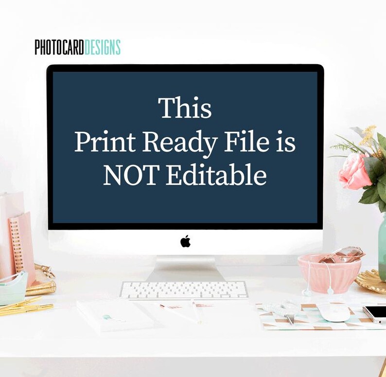 Puede incluir: Un monitor de computadora de escritorio que muestra el texto This Print Ready File is NOT Editable en fuente blanca sobre un fondo azul oscuro. El monitor se encuentra sobre un escritorio blanco con suministros, un cuenco rosa y flores.