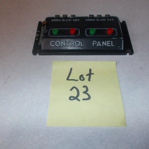 May include: Black control panel with two red and green lights. The panel has the text "GREEN BLACK RED" and "CONTROL PANEL" printed on it. A yellow sticky note with the text "Lot 23" is in the foreground.