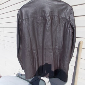 May include: A brown leather jacket with a button-up collar and long sleeves.