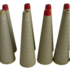 May include: A collection of ten empty, conical yarn spools made of textured, light brown cardboard. Each spool features a distinct, bright red painted tip at the narrow top end, with a spiraling, grooved surface pattern running along the length.