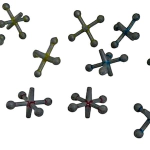 May include: A collection of jacks, a classic game toy, scattered against a white background. The jacks are primarily gray with accents of yellow, blue, and red. Each jack has a cross-shaped body with rounded ball ends.