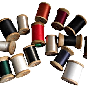 May include: A collection of vintage wooden spools filled with colorful threads. The spools are in various colors, including black, red, white, and green. The spools are arranged on a white background, creating a visually appealing display for sewing or craft projects.