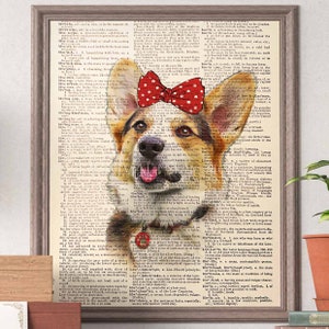 May include: Framed print featuring a Corgi dog with a red polka dot bow on its head, set against a vintage dictionary page background. The dog's tongue is visible. The frame is a neutral brown color.