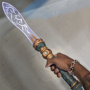 Op de afbeelding: Een futuristisch, gloeiend zwaard met een transparant blad met witte, organische patronen. Het handvat is een combinatie van goud, teal en brons, met ingewikkelde details. Het zwaard wordt in een hand gehouden, wat het ontwerp benadrukt.