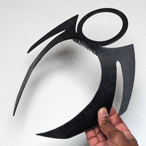 Può includere: Fascia per capelli in plastica nera con un design geometrico. La fascia è a forma di mezzaluna con due punte su entrambi i lati.