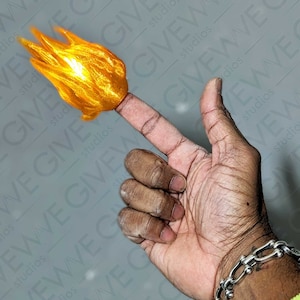 May include: A hand with a fingertip that has a flame-shaped object attached to it. The flame is a bright yellow and orange colour.
