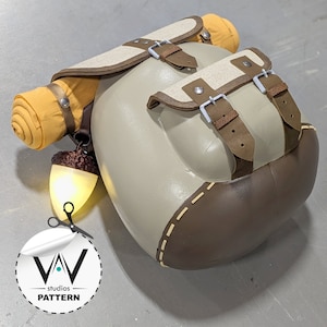 Puede incluir: Una mochila marrón y beige con un saco de dormir amarillo enrollado adjunto. La mochila tiene una correa y una hebilla de cuero marrón. La mochila tiene una luz marrón claro en forma de bellota unida al lateral.