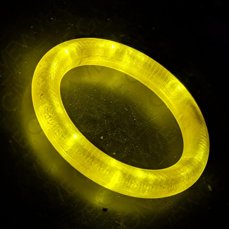 Puede incluir: Un anillo brillante de color amarillo que brilla con una superficie lisa y texturizada.