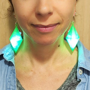 May include: A pair of green and white diamond-shaped earrings with a light blue swirl pattern.