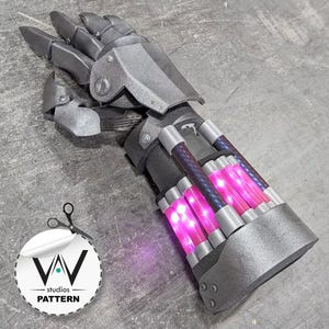 May include: A metallic silver gauntlet featuring articulated finger plates and a forearm section equipped with four glowing pink cylindrical tubes. The structure includes dark grey accents and mechanical detailing, with a circular logo reading VAV studios PATTERN.