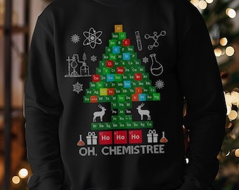 May include: Black sweatshirt featuring a Christmas tree design made of periodic table elements. The tree is decorated with snowflakes, deer, and gifts. The text "OH, CHEMISTREE" is printed at the bottom.