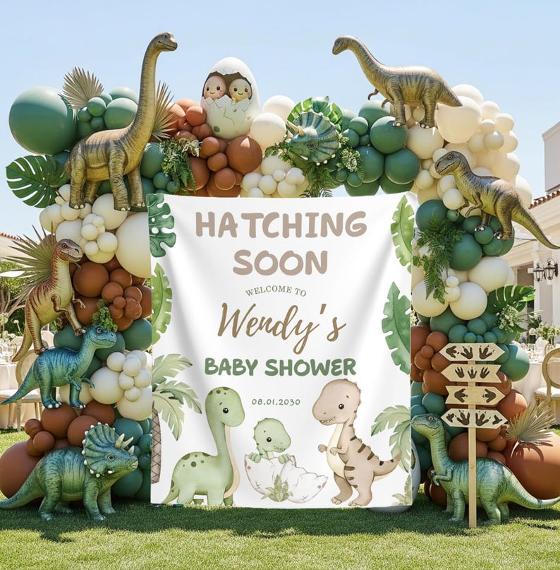 May include: A dinosaur-themed baby shower decoration with a white banner that reads "Hatching Soon Welcome to Wendy's Baby Shower 08.01.2030". The arch is decorated with green, brown, and white balloons, and dinosaur figurines.