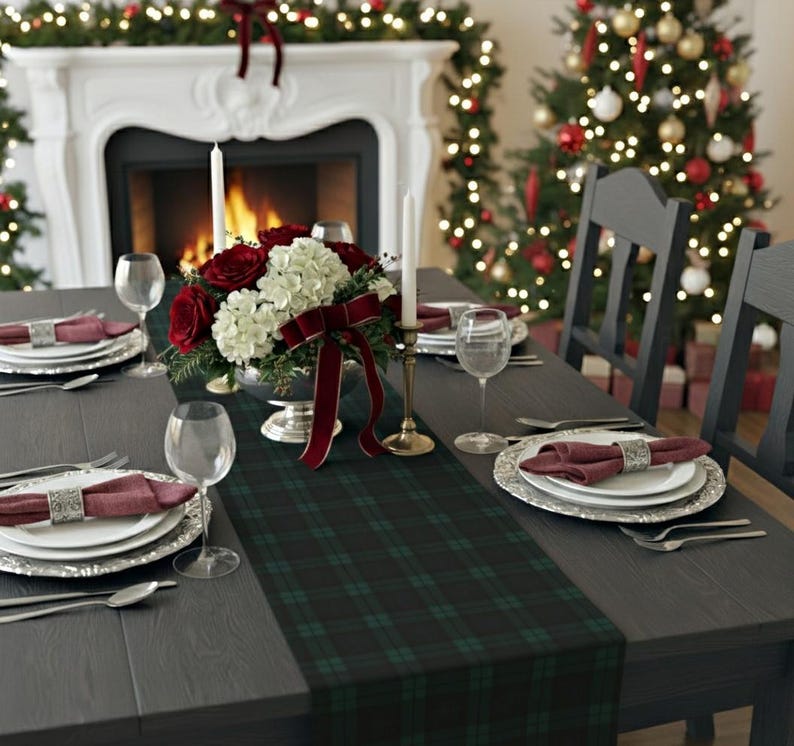 May include: A dark green and black plaid table runner centered on a dark wooden dining table. The table is set with white plates, maroon cloth napkins in silver rings, clear wine glasses, and a centerpiece of red roses and white hydrangeas.