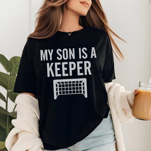 Camiseta de mamá futbolera, regalo para el Día de la Madre, camiseta de mamá portera, sudadera con capucha para mamá futbolera, regalo para mamá deportista UNISEX TEE BLACK