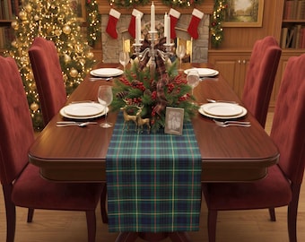 May include: A rectangular wooden dining table featuring a green, blue, and yellow plaid table runner. The table is set with white plates, silverware, and clear glasses. A silver candelabra, two gold reindeer figurines, and a small picture frame sit atop.