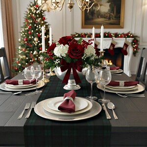 May include: A formal dining table setting featuring a dark green plaid runner, white plates, burgundy napkins with silver rings, clear wine glasses, and silver cutlery. A centerpiece of red roses, white hydrangeas, and berries sits in a silver bowl.