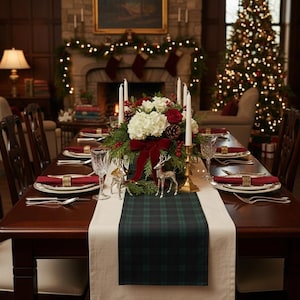 May include: A dining table set for a holiday meal featuring a dark green and navy blue plaid table runner over a cream cloth. The centerpiece includes white hydrangeas, red roses, pinecones, greenery, a velvet bow, and four tall white candles.