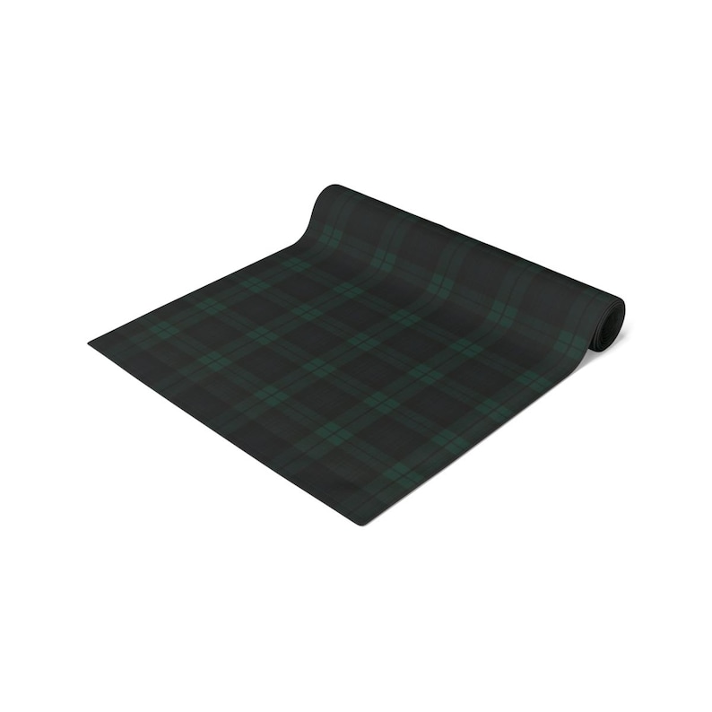 May include: A rectangular table runner featuring a dark charcoal gray and forest green plaid pattern. The fabric is partially rolled at one end, displaying a consistent tartan design with intersecting thin lines across the surface.
