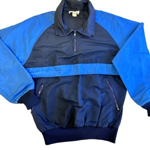 May include: A blue and navy blue windbreaker jacket with a zip closure and two zipped pockets.