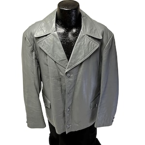 May include: A gray leather jacket with a classic design. The jacket features a notched collar, three-button closure, and two front pockets. The jacket is displayed on a black mannequin.