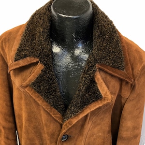 May include: A brown suede jacket with a brown faux fur collar. The jacket has a button closure and a pointed collar.