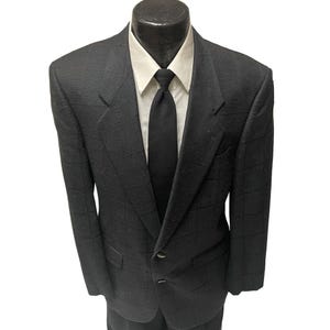 May include: A black blazer with a subtle checkered pattern. The blazer has a single button closure and a classic fit.
