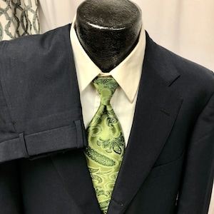 May include: A dark blue suit jacket with a green paisley patterned tie. The jacket has a single button closure and a notched lapel.
