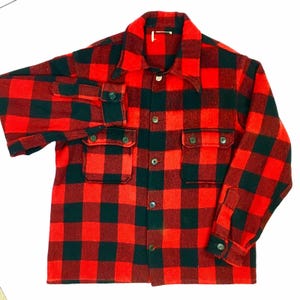Puede incluir: Camisa de franela a cuadros rojos y negros de manga larga, con botones en la parte delantera y dos bolsillos en el pecho.