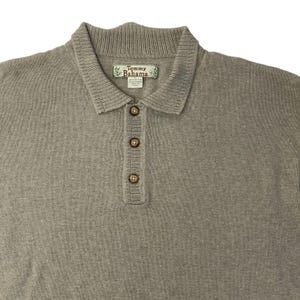 May include: A light brown long-sleeved knitted polo shirt with a button-up collar and a Tommy Bahama brand label.