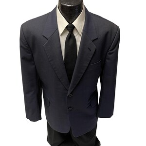 May include: A dark blue blazer with a three-button closure and a black tie.